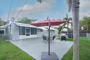 a patio with a red umbrella next to a house at Rachaels Upscale Two Bedrooms Luxury Home in Fort Lauderdale