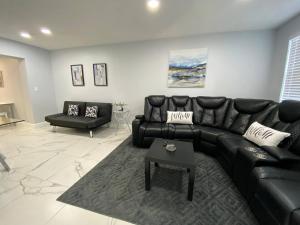 a living room with a black leather couch and a table at Mazor Luxury Three Bedrooms Vacation Home in Fort Lauderdale