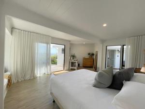 a white bedroom with a large bed and a window at Sea View Estate - Waiheke Escapes in Onetangi