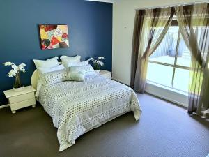 Dormitorio azul con cama y ventana en Premium Barossa Getaway, en Tanunda