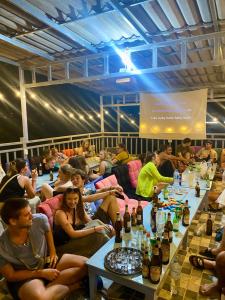 um grupo de pessoas sentadas numa sala com garrafas de vinho em Sunrise Riverside Pool Hostel em Luang Prabang