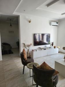 a living room with chairs and a tv on a wall at Dvyne Luxury Home in Ikeja