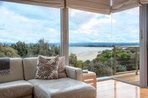 a living room with a couch and a large window at Sea View ~ ultimate beachside retreat! in Coles Bay