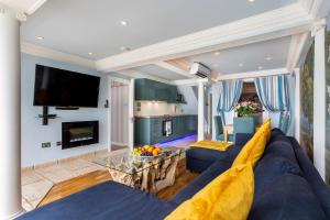 a living room with a blue couch and a tv at The Breakers - Riviera Apartment in Sandgate