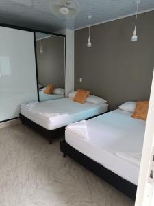two beds in a room with a mirror at HOSPEDAJE EL ENSUEÑO in Doradal