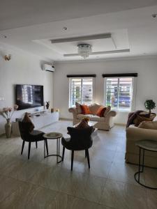 een woonkamer met banken en stoelen en een televisie bij Dvyne Luxury Home in Ikeja