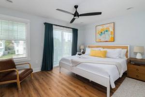 a bedroom with a bed with a ceiling fan and a chair at Be A Nomad - Perfect for groups - Brand New in Jacksonville Beach