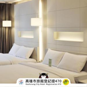 two beds in a hotel room with white pillows at Kindness Hotel - Zhongshan Bade Branch in Kaohsiung