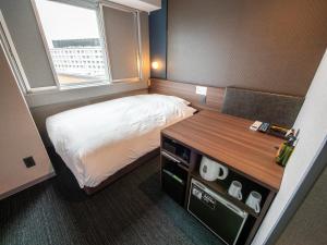 a small room with a bed and a desk and a window at Super Hotel Premier JR Nara Eki in Nara