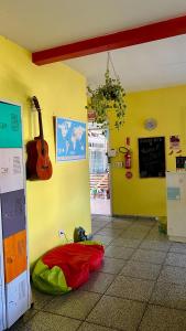 een gele kamer met een gitaar aan de muur bij Pequi hostel in Florianópolis