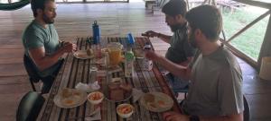 Kichwa Lodge في Aguarico: مجموعة من الرجال يجلسون حول طاولة يأكلون الطعام