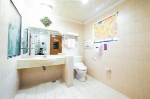 a bathroom with a sink and a toilet and a mirror at Wen Sha Bao Motel-Xinying in Xinying