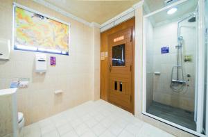 a bathroom with a shower and a wooden door at Wen Sha Bao Motel-Xinying in Xinying