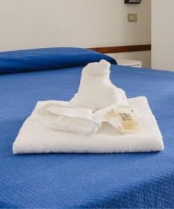 un par de toallas blancas en una cama azul en Hotel Arena, en Cattolica