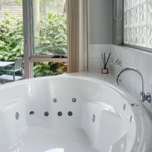 a white bath tub in a bathroom with a window at Waves Luxury Suites in Port Campbell
