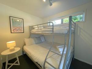 1 dormitorio con 1 litera, 1 cama y 1 mesa en Oneroa Village Beach House- Waiheke Escapes, en Oneroa