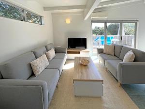 sala de estar con sofá y mesa de centro en Oneroa Village Beach House- Waiheke Escapes, en Oneroa