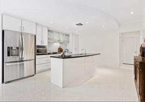 a kitchen with white cabinets and stainless steel appliances at Premium Barossa Getaway in Tanunda