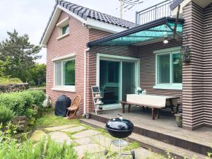 a house with a wooden deck with a bench on it at Sodamhyang Pension in Jeju