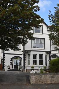 a white house with a tree in front of it at Abbey House in Llandudno