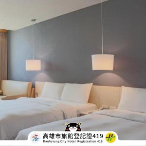 two beds in a room with two lights on the wall at Kindness Hotel - Kaohsiung Guang Rong Pier in Kaohsiung