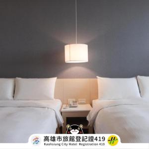 a room with two beds and a table with a lamp at Kindness Hotel - Kaohsiung Guang Rong Pier in Kaohsiung
