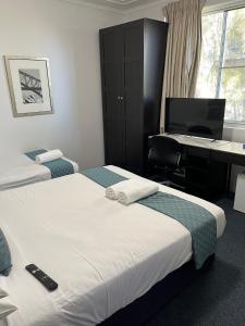 a room with two beds and a desk with a computer at Hotel St Leonards in Sydney