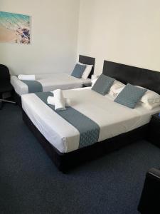 three beds in a hotel room with at Hotel St Leonards in Sydney