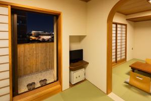 um quarto com uma televisão e uma janela em Ryokan Asakusa Shigetsu em Tóquio