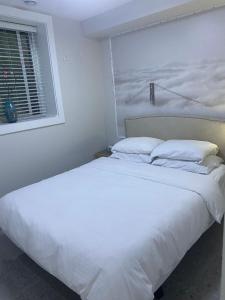 a large white bed in a bedroom with a window at Panorama VistaVue Vancouver in Vancouver