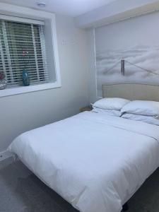 1 cama blanca en un dormitorio con ventana en Panorama VistaVue Vancouver en Vancouver