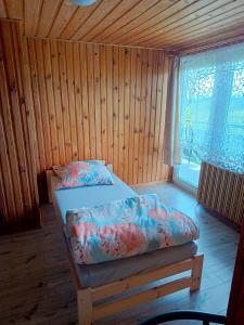 Cama en habitación de madera con ventana en Noclegi u Ewusi 2 en Januszowice