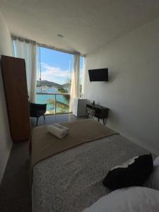 a bedroom with a bed and a large window at Pousada do Mirante do Atalaia in Arraial do Cabo