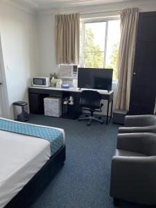 um quarto com uma cama e uma secretária com um computador em Greenwich Inn Motel em Sidney