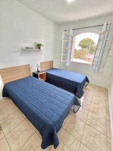 two beds in a room with a window at Apartamento Grande - Privado - 3 quartos com 1 suíte in Piracicaba