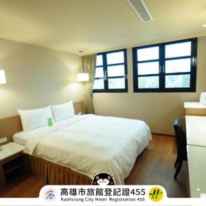 a bedroom with a large bed and two windows at Kindness Hotel - Kaohsiung Main Station in Kaohsiung