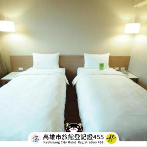 2 camas en una habitación de hotel con sábanas blancas en Kindness Hotel - Kaohsiung Main Station, en Kaohsiung