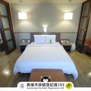una camera da letto con un grande letto bianco con due tavoli di Kindness Hotel - Hanshen a Kaohsiung