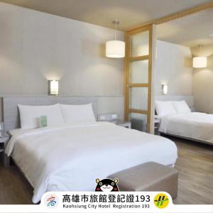 una camera da letto con un grande letto bianco e uno specchio di Kindness Hotel - Hanshen a Kaohsiung