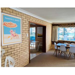ein Zimmer mit einem Tisch, Stühlen und einem Sonnenschirm in der Unterkunft Bay Motel in Byron Bay