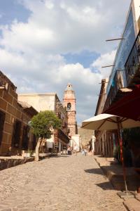 een stadsstraat met een klokkentoren in de verte bij Casa Grande - Adults Only in Real de Catorce