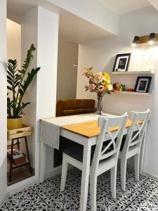 uma mesa de jantar com cadeiras brancas e um vaso de flores em GREEN Apartment em Riga
