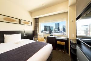 una camera d'albergo con letto, scrivania e finestra di remm Akihabara a Tokyo