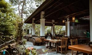 an outdoor patio with tables and chairs and trees at Tak Andaman Resort & Hotel in Tak