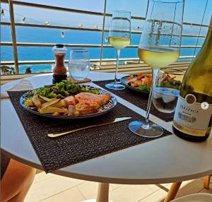 a table with a plate of food and a bottle of wine at Frente a la playa. Vista al mar. in Concón
