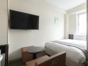 a hotel room with a bed and a flat screen tv at Vessel Inn Hiroshima Ekimae in Hiroshima