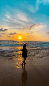 Una mujer caminando por la playa al atardecer en Lucky Prince Villa, en Aluthgama