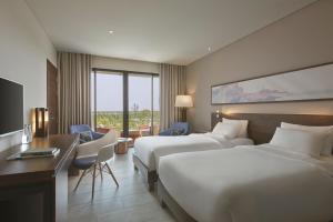 a hotel room with two beds and a desk at Novotel Phu Quoc Resort in Phú Quốc