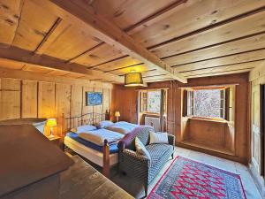 a bedroom with a bed and a chair in a room at La Maison du Bassin - Grand St Bernard - Orsieres in Orsières