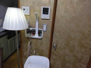 ein Zimmer mit einer Lampe und einem Wii-Controller an der Wand in der Unterkunft Suiren in Nagoya + 7 Fotos